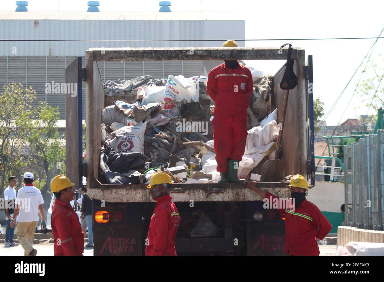 les nettoyeurs en uniforme ramassant les déchets dans un camion à ordures dans la zone portuaire Banque D'Images