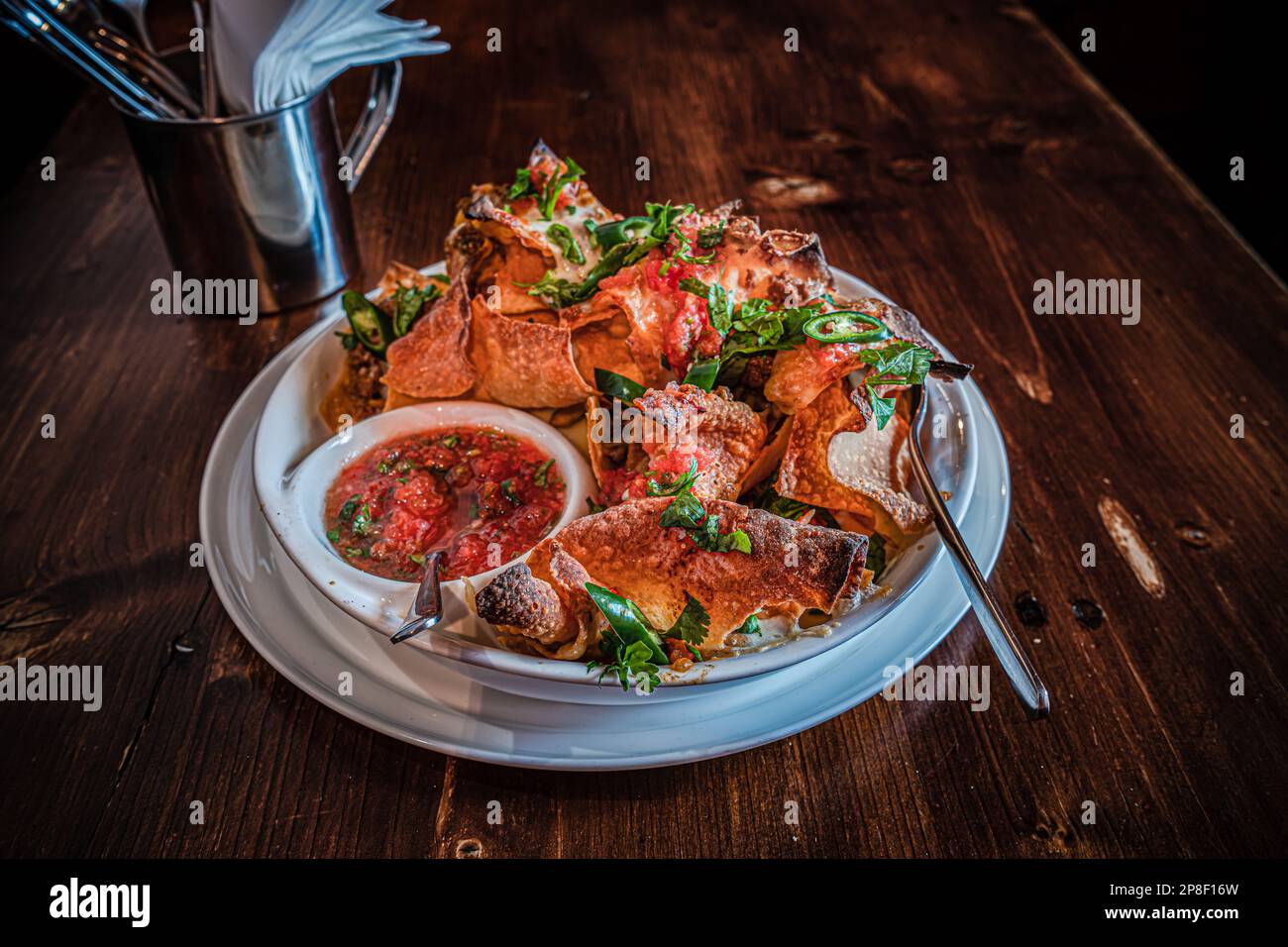 Gros plan d'une assiette de chips avec de la viande, du fromage fondu, des herbes, du piment vert et de la sauce à la sauce tomate Banque D'Images