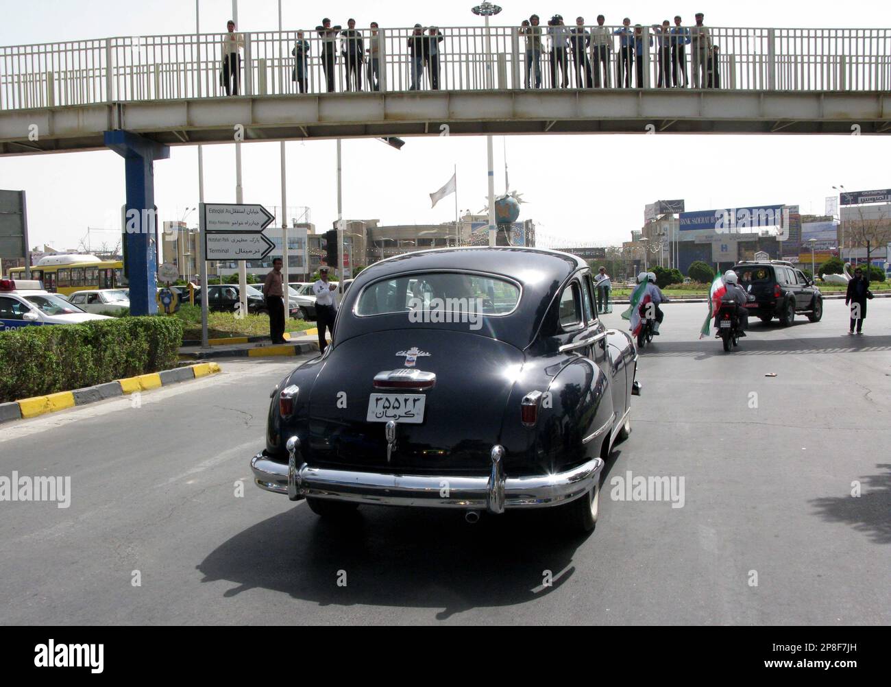Spectators on a bridge watch as a car which was used to exile Reza Shah Pahlavi, an army officer who became the ruler of Iran and founder of the Pahlavi dynasty in 1925, after Iran was occupied by Soviet Union and British in 1941, is preceded by Iranian officials riding motorcycles carrying Iranian national flags during world museum day Monday May 18, 2009, in Kerman, Iran, 1,040 kms (624 miles) south of Tehran. (AP Photo/Hasan Sarbakhshian) Banque D'Images