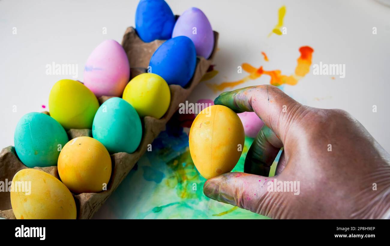 Fond coloré avec main tenant l'oeuf de Pâques et la copie Banque D'Images
