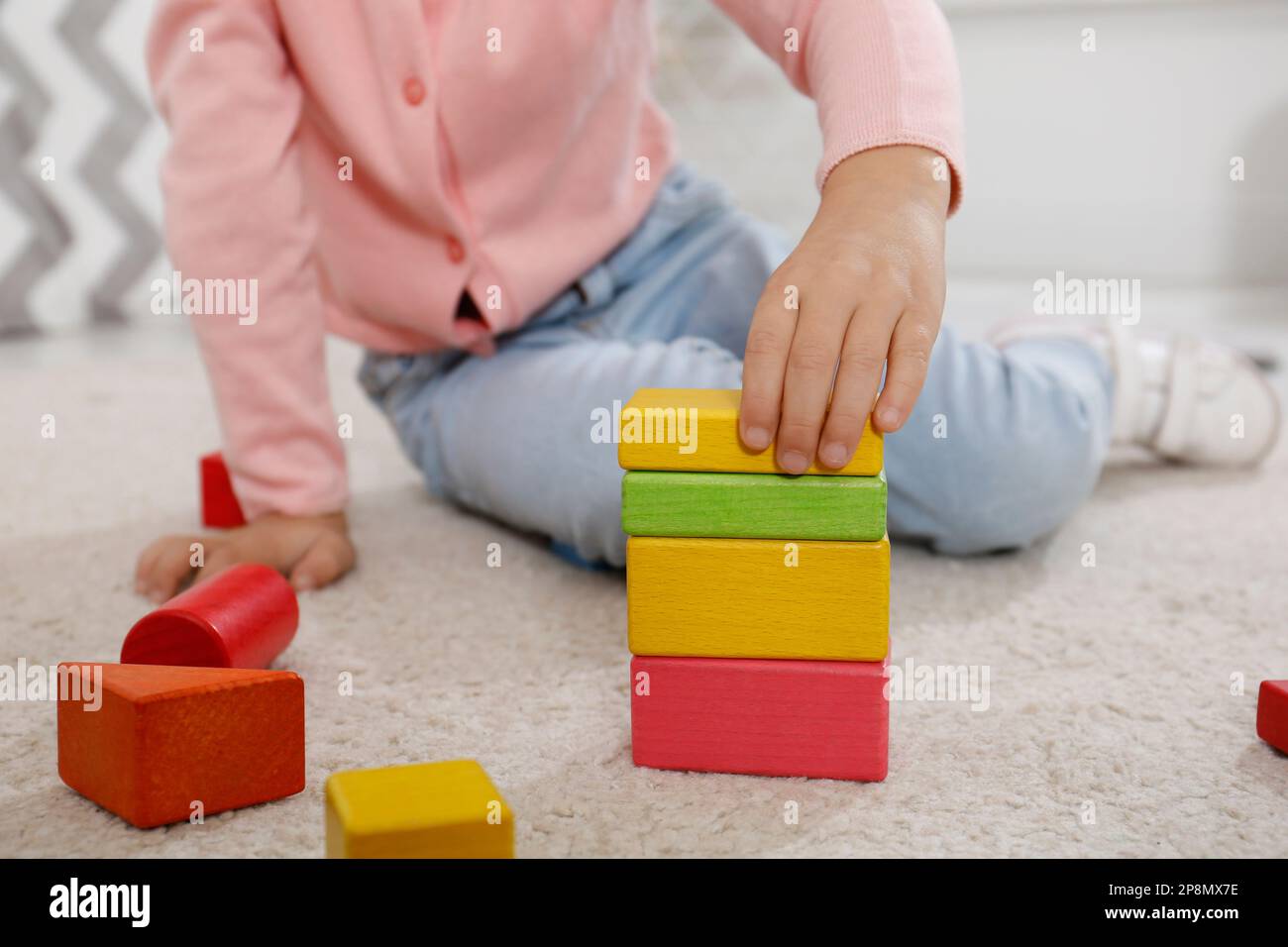 Jolie petite fille jouant avec des blocs de construction colorés à l'intérieur, gros plan Banque D'Images