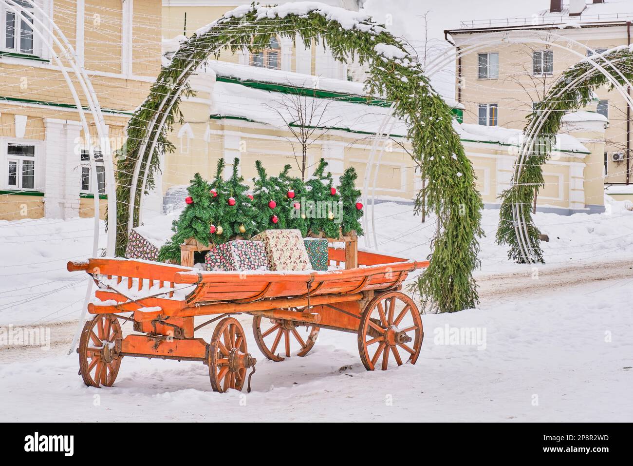 Décoration extérieure pour les vacances d'hiver. Sur un vieux chariot en bois peint brillant arbres de Noël avec des boules de Noël, boîtes avec des cadeaux. Arc de bois d'épicéa Banque D'Images
