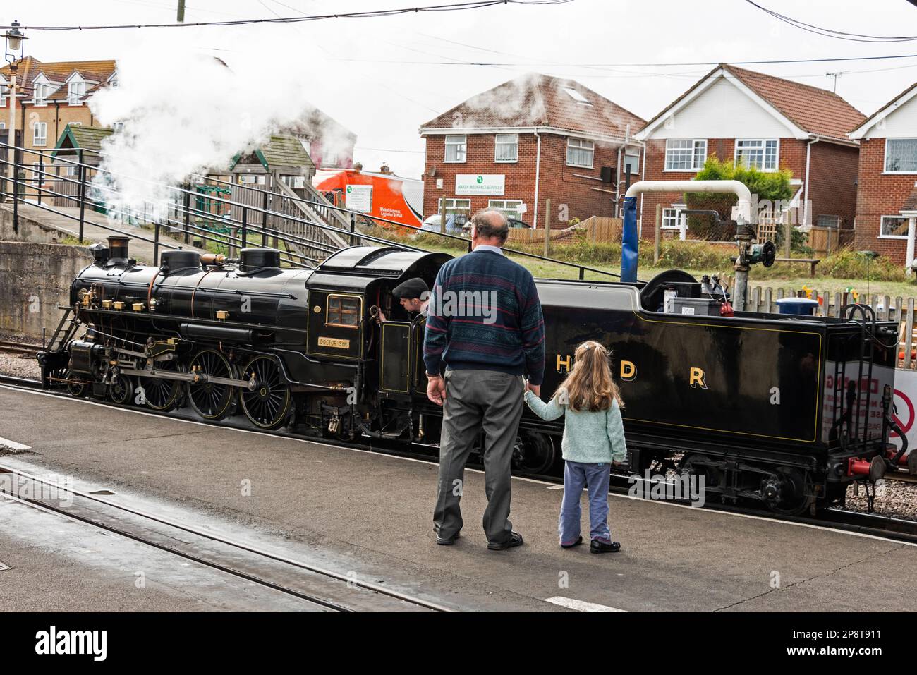 Un père et sa jeune fille regardent alors que le petit train part du chemin de fer miniature Romney Hythe & Dymchurch qui s'étend le long de Romney Banque D'Images
