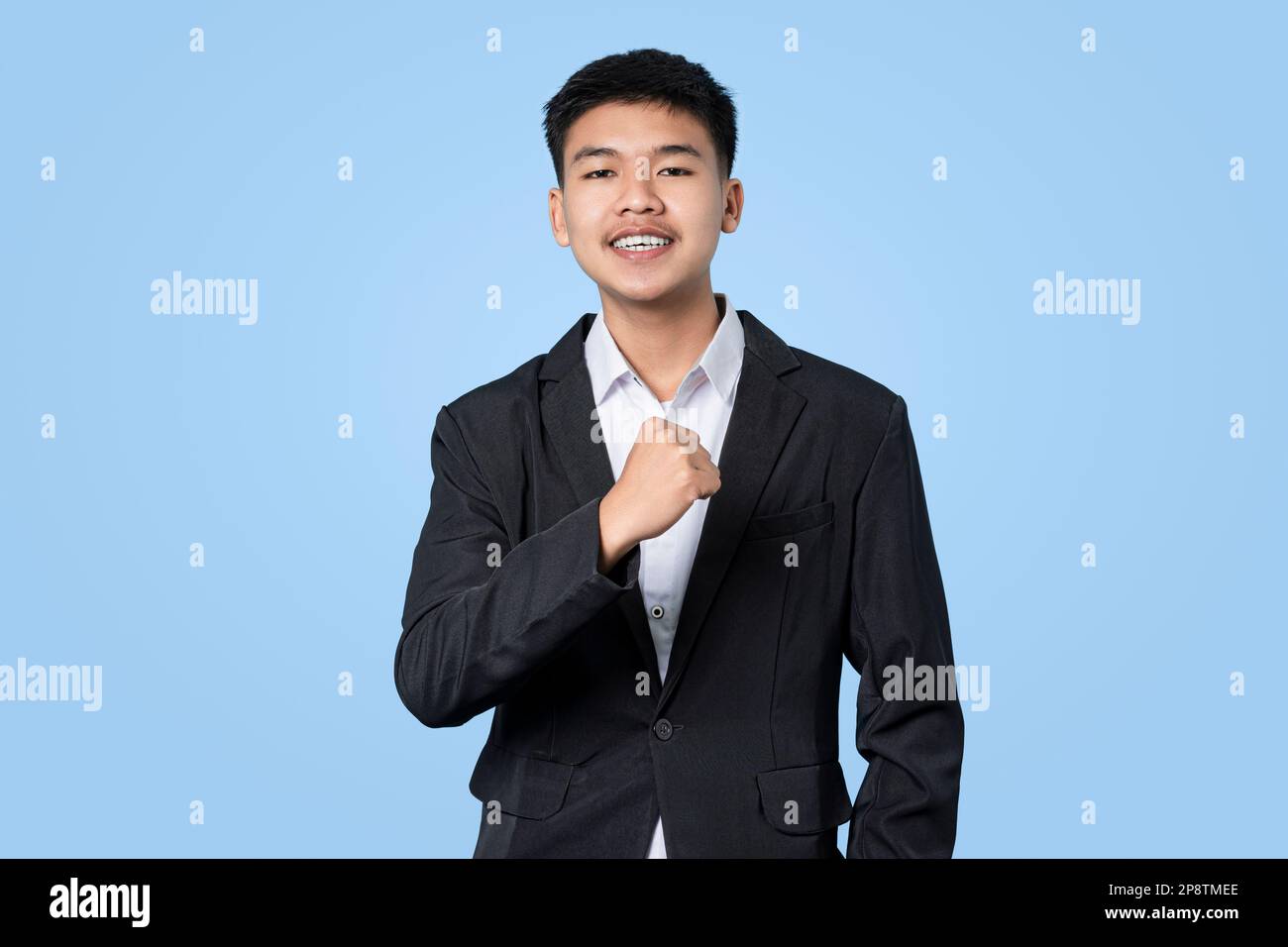 Un jeune homme d'affaires asiatique séduisant se réjouit de célébrer le succès isolé sur fond bleu clair Banque D'Images