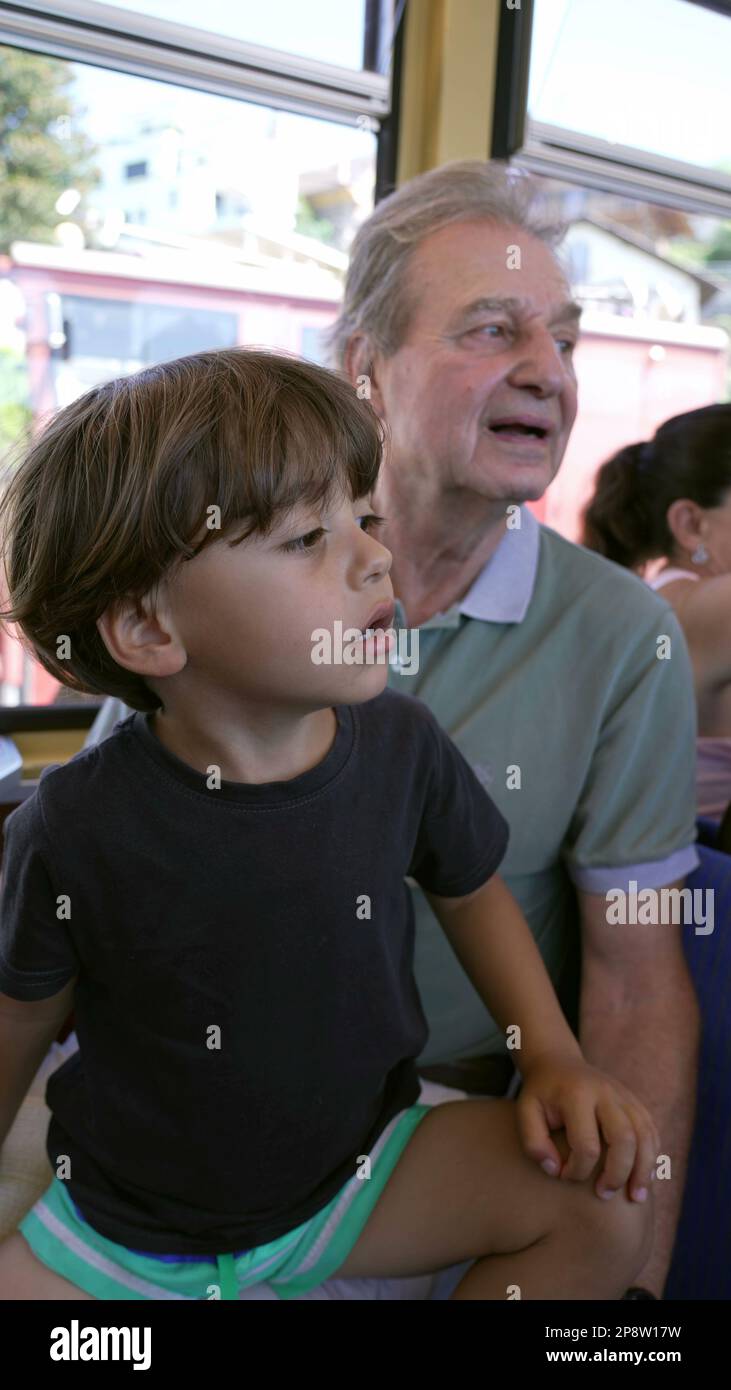 Petit-fils voyageant en train avec grand-père. Petit garçon assis sur grand parent tour à l'intérieur de transport de chemin de fer en mouvement dans la vidéo verticale Banque D'Images