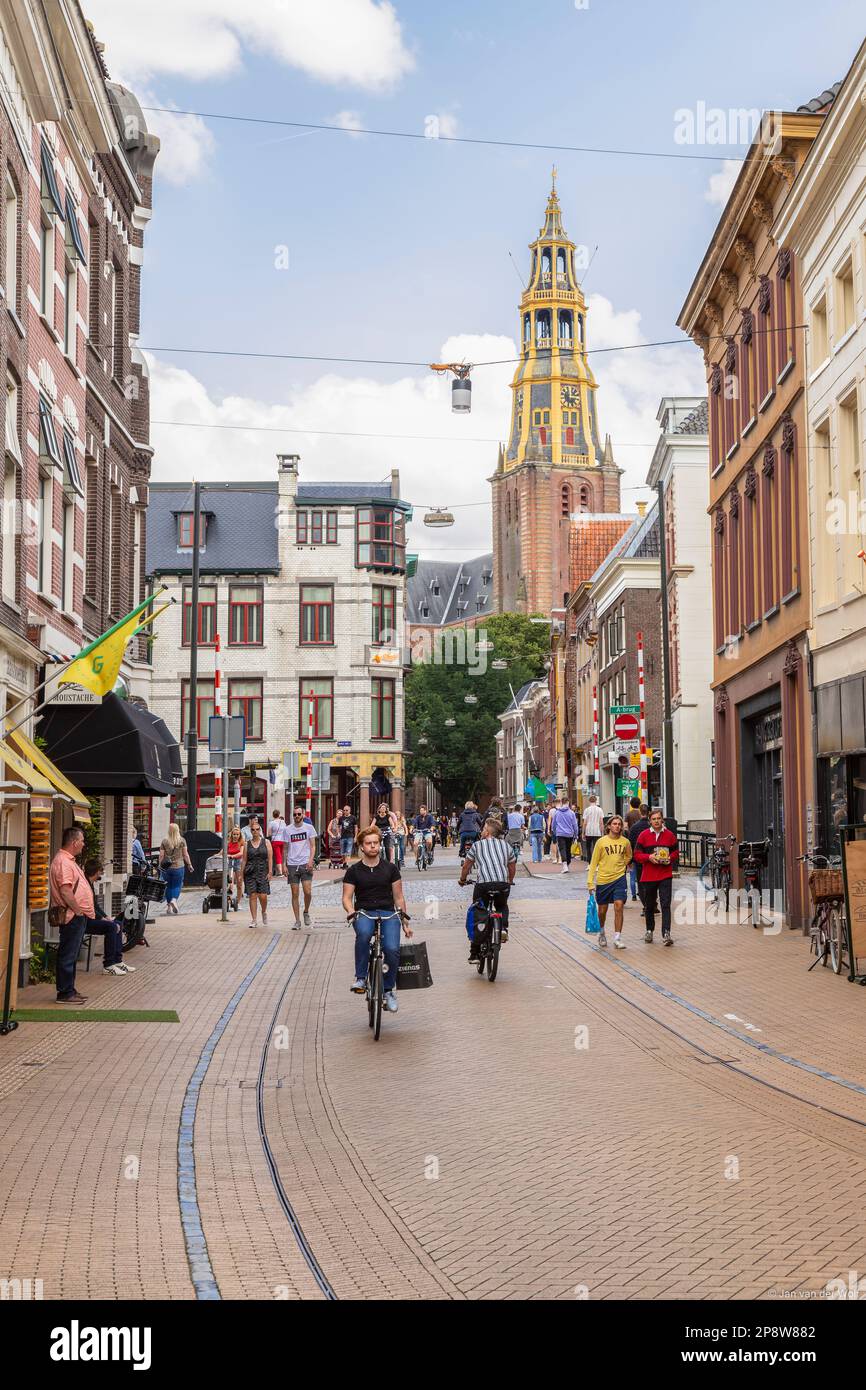Rue commerçante animée avec la tour de l'église historique Der AA à Groningen. Banque D'Images