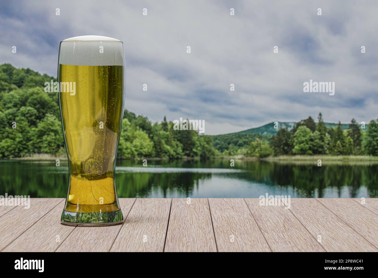 Verre de bière légère sur la table avec vue sur la forêt et le lac Banque D'Images