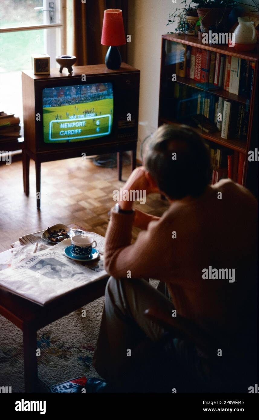 Royaume-Uni, Angleterre. 1977. Un homme est assis dans son salon et regarde un match de rugby à la télévision. Banque D'Images