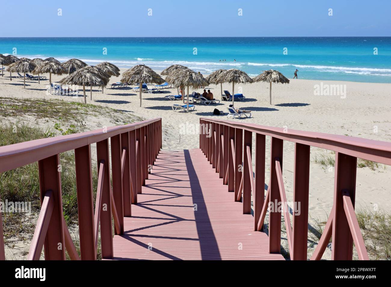 Escaliers menant à la plage tropicale avec sable blanc, parasols en osier et personnes bronzantes. Vue pittoresque sur la côte océanique, station touristique sur l'île des Caraïbes Banque D'Images