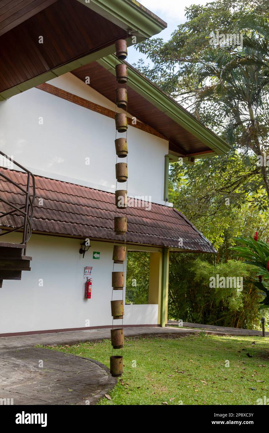 Muelle San Carlos, Costa Rica - Une chaîne de pluie draine l'eau de pluie du toit d'un bâtiment du Tilajari Hotel Resort. Banque D'Images