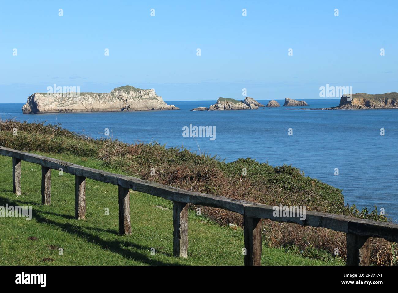 Isla de los Conejos en la villa de Suances, por entan las aguas del mar cantábrico a su playa de la Concha, con valla de madera y prado verde. Banque D'Images