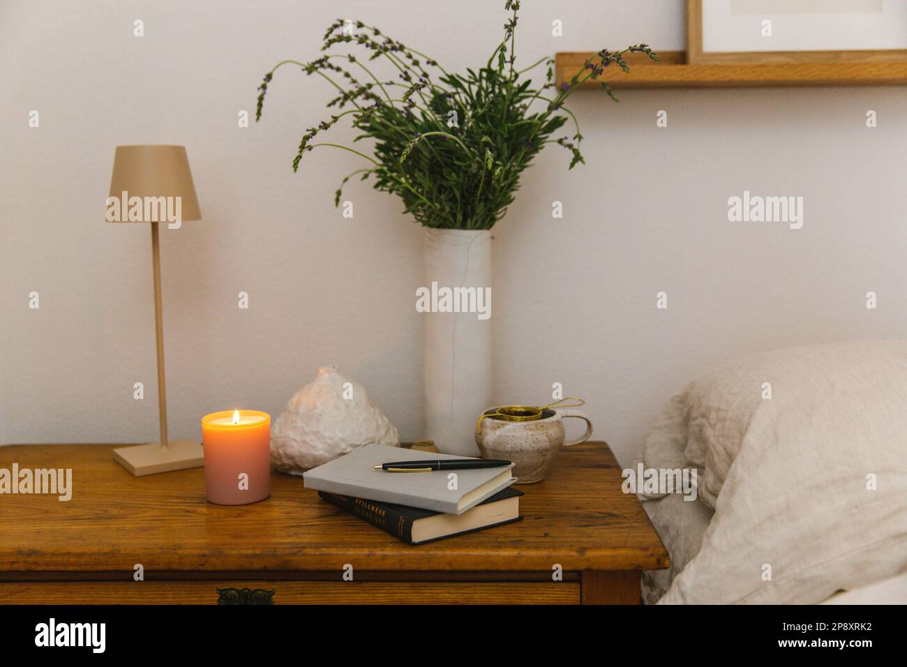 Une table de chevet éclairée aux chandelles est prête avec du thé et un journal frais pour un moment de soins personnels Banque D'Images