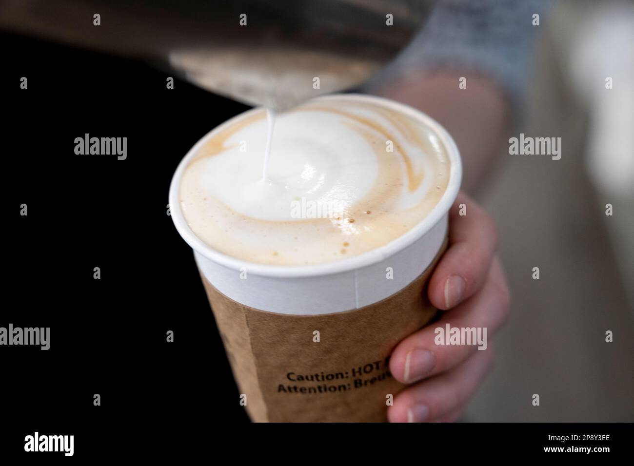 Espresso dans une tasse en papier blanc avec du lait cuit à la vapeur versé sur le dessus Banque D'Images