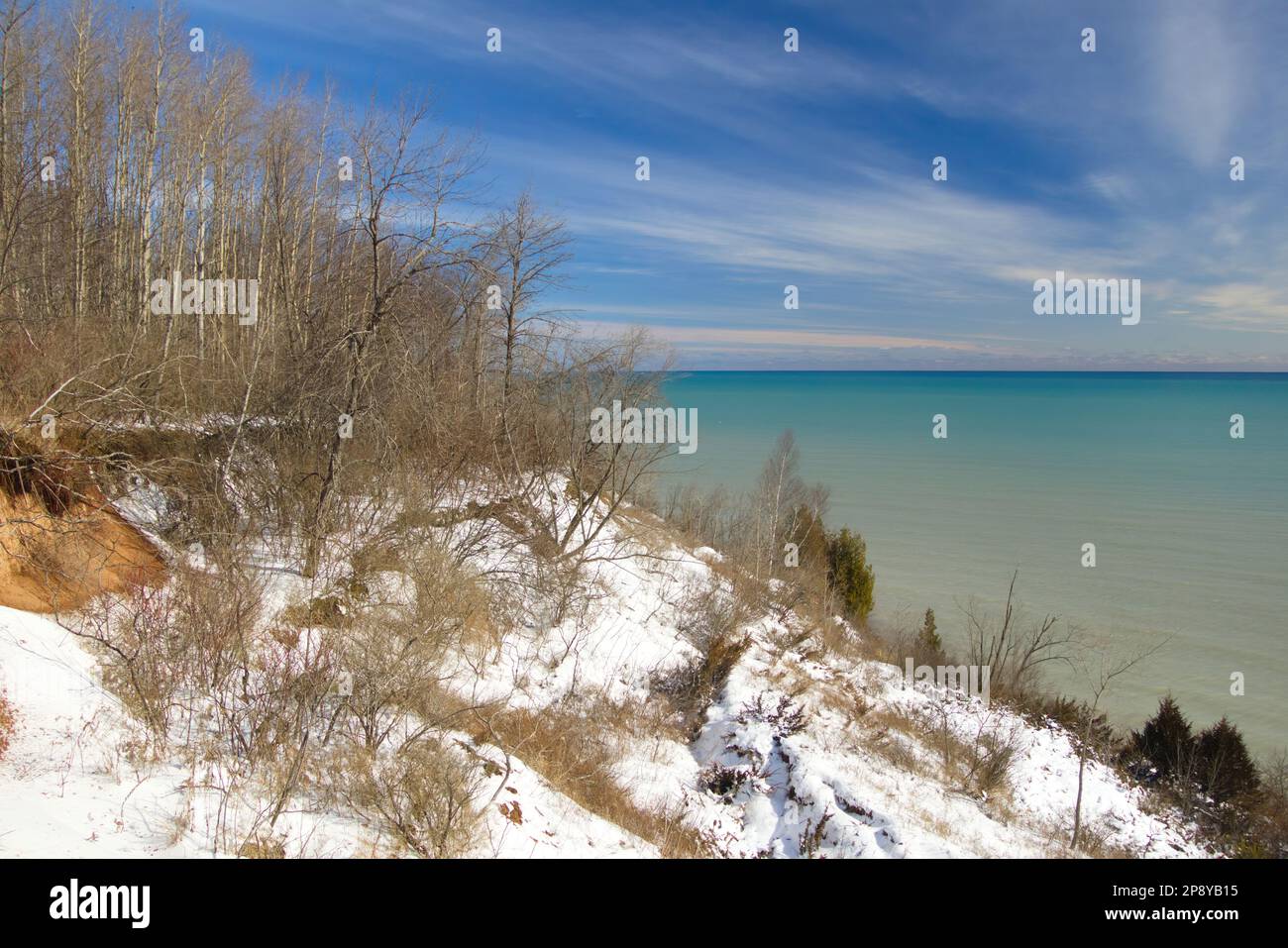 Depuis le sommet d'un promontoire couvert de neige et de forêt, par une belle journée d'hiver, la vue sur un lac Michigan paisible. Banque D'Images