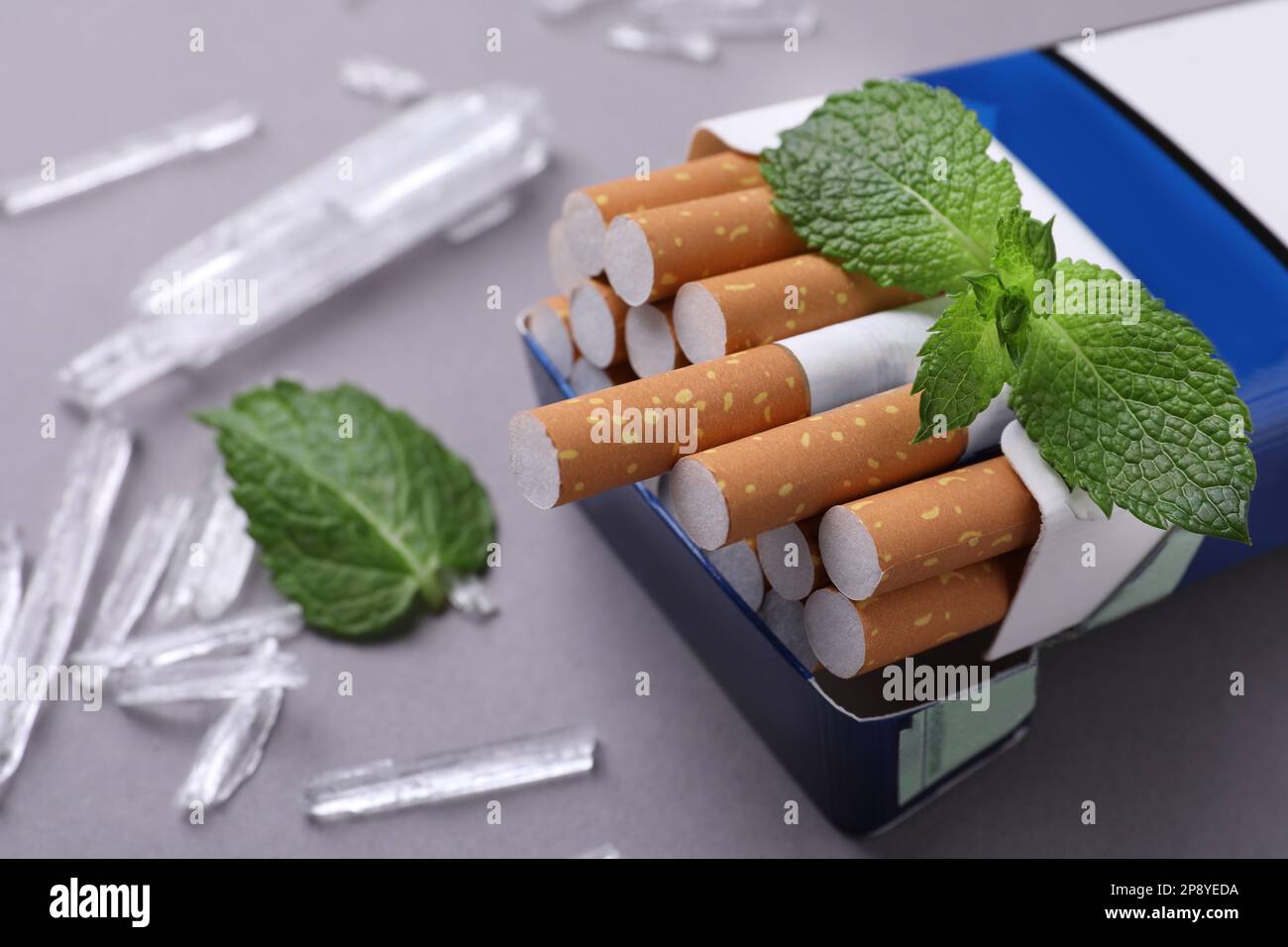 Paquet de cigarettes, de cristaux de menthol et de feuilles de menthe sur fond gris, gros plan Banque D'Images