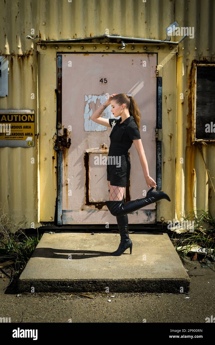 Belle jeune femme debout devant le bâtiment en métal | style Goth | Romper noir | Rusty | vue latérale Banque D'Images