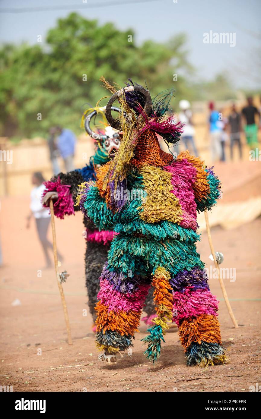 Deux porteurs de masques en fibres colorées se font voir au Festival Festima de Dedougou, au Burkina Faso Banque D'Images