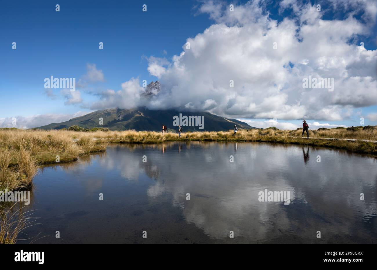 Circuit de randonnée de Pouakai pour quatre personnes. Le Mt Taranaki se reflète dans le tarn. Parc national d'Egmont. Taranaki. Nouvelle-Zélande. Banque D'Images