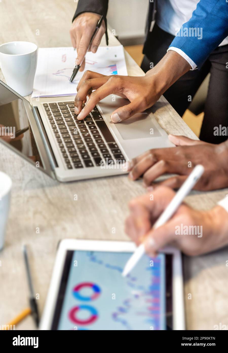 Par-dessus Crop collègues anonymes travaillant sur la stratégie d'entreprise à l'aide d'un ordinateur portable et d'une tablette avec des diagrammes pendant la collaboration au bureau Banque D'Images