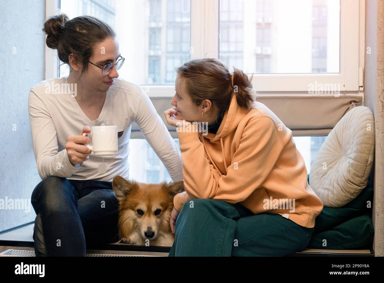 bonne fille, garçon et chien corgi assis sur le rebord de la fenêtre Banque D'Images