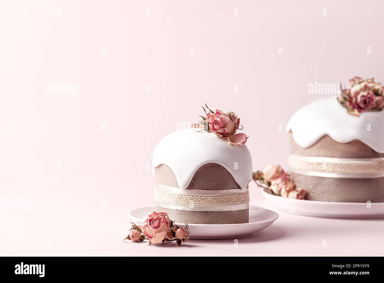 Gâteaux de Pâques émaillés décorés de fleurs de rose de thé sur fond rose pastel. Arrière-plan de vacances avec espace de copie pour votre conception. Banque D'Images