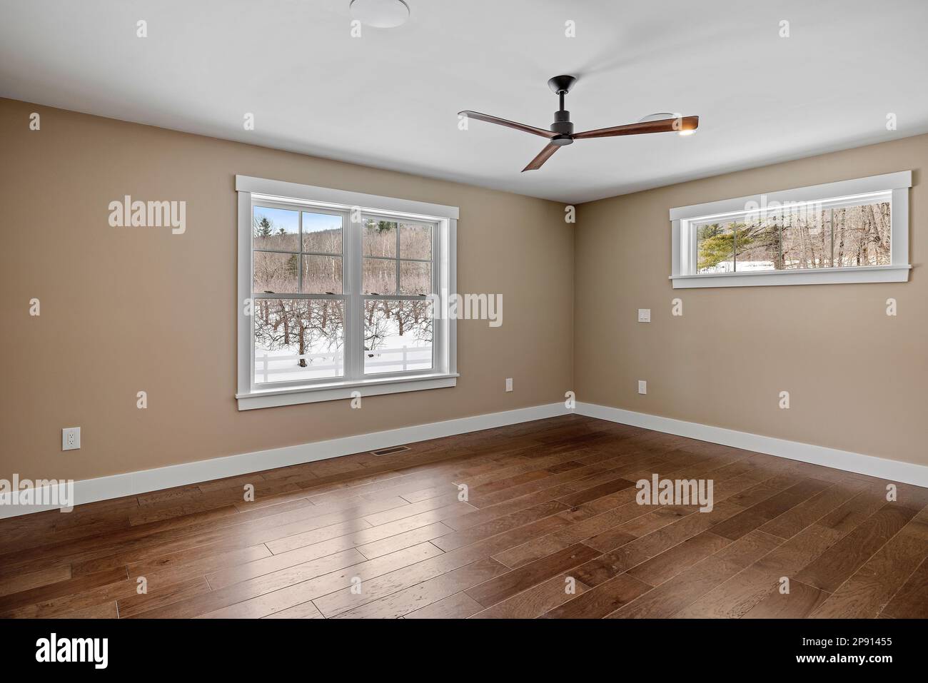 Une grande chambre vide avec un ventilateur de plafond et du parquet Banque D'Images