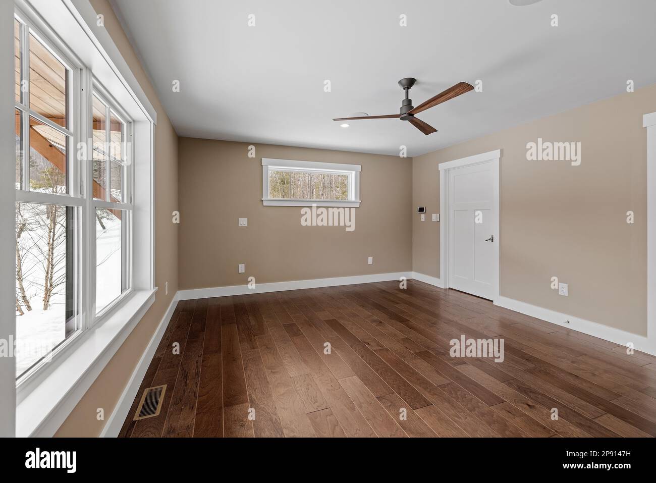 Une grande chambre vide avec un ventilateur de plafond et du parquet Banque D'Images