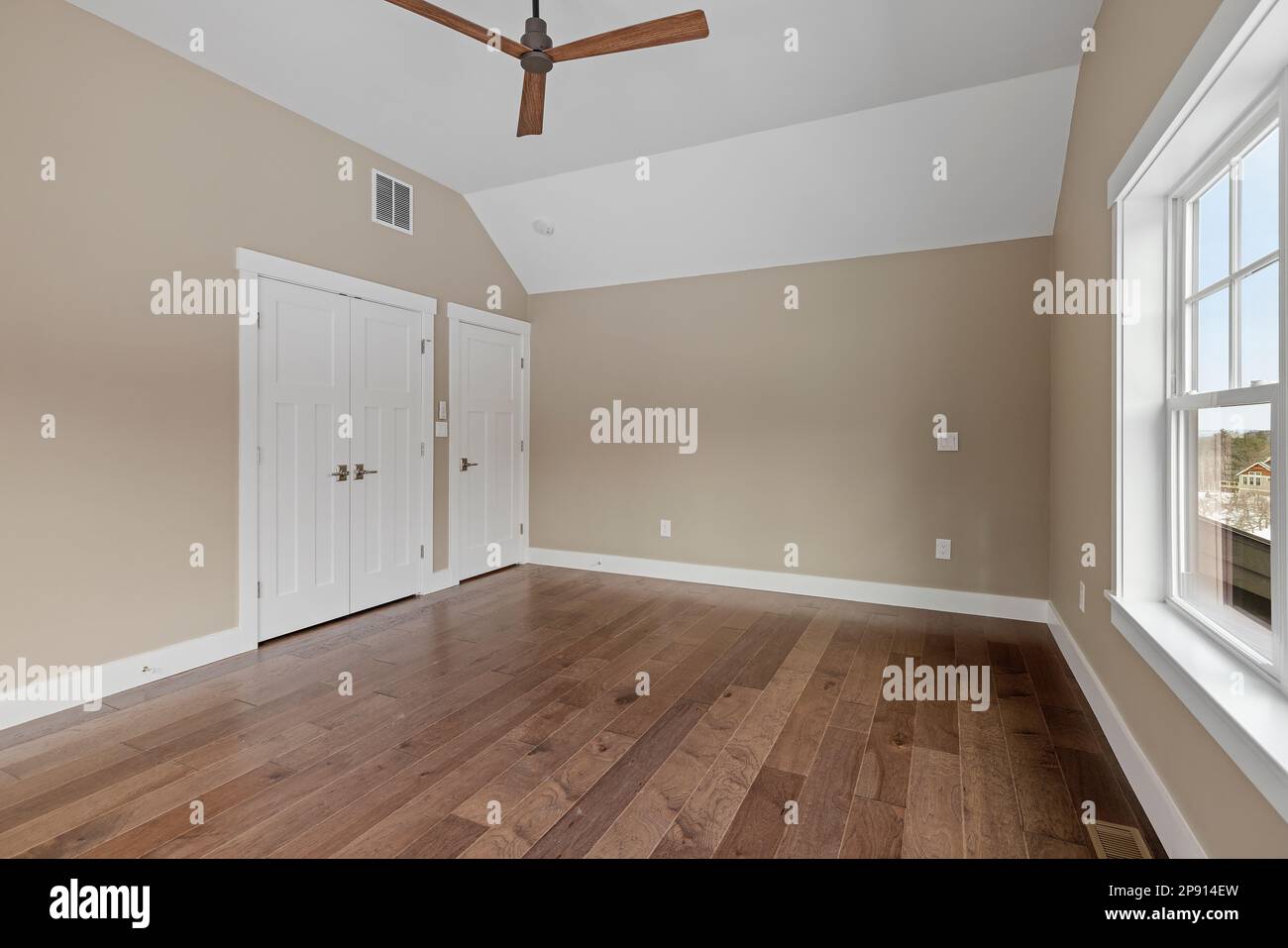 Un intérieur de salon moderne présentant du parquet, un ventilateur de plafond et de grandes fenêtres Banque D'Images