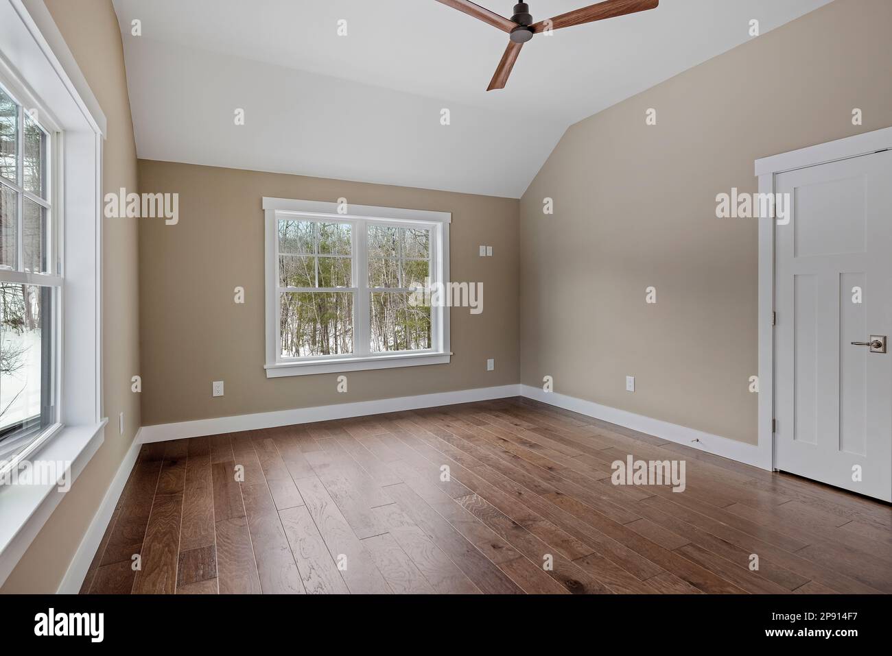 Un intérieur de salon moderne présentant du parquet, un ventilateur de plafond et de grandes fenêtres Banque D'Images