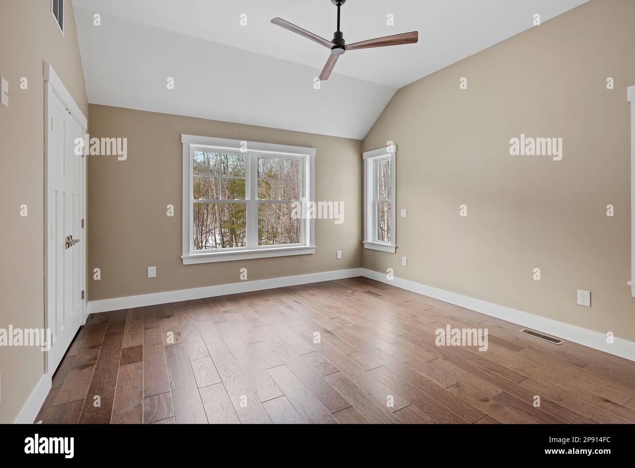 Cette chambre vide est dotée de parquet, d''un ventilateur de plafond et de murs marron blancs Banque D'Images