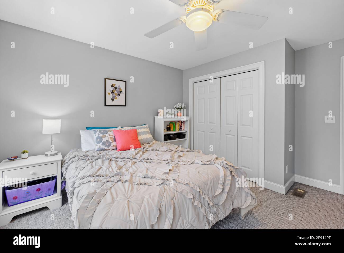 La chambre blanche et confortable dispose d''un petit lit et d''un ventilateur de plafond Banque D'Images