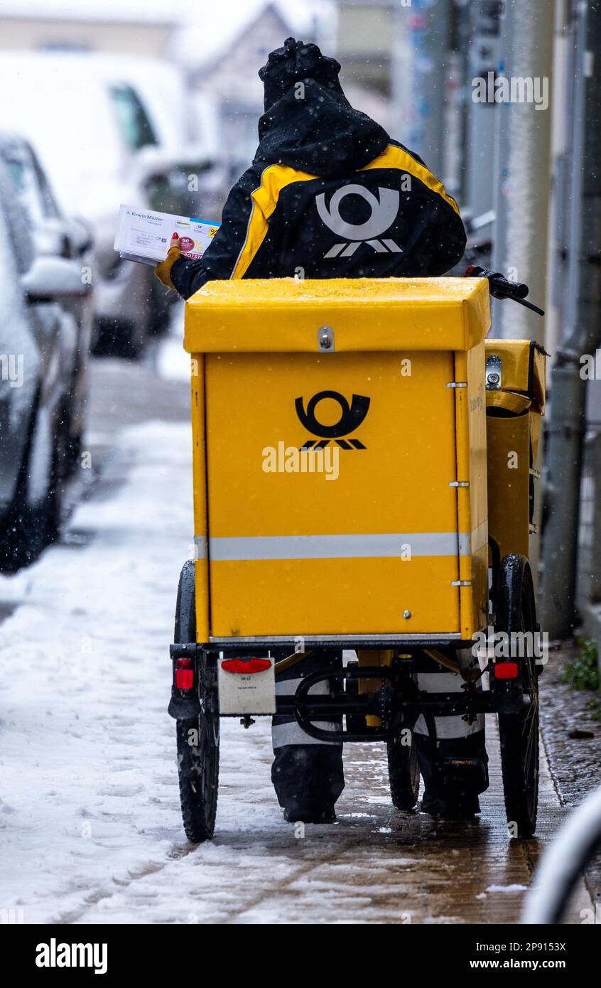 Schwerin, Allemagne. 10th mars 2023. Un porte-lettre est à son vélo dans la neige abondante dans la vieille ville. En ce qui concerne 10 mars 2023, commence le cycle de négociations de 4th dans le conflit de négociation collective à Deutsche Post. Il s'agit d'une nouvelle convention collective pour environ 160 000 salariés de la division Post & Paket Deutschland Group. Verdi exige une augmentation de salaire de 15 pour cent. Credit: Jens Büttner/dpa/Alay Live News Banque D'Images