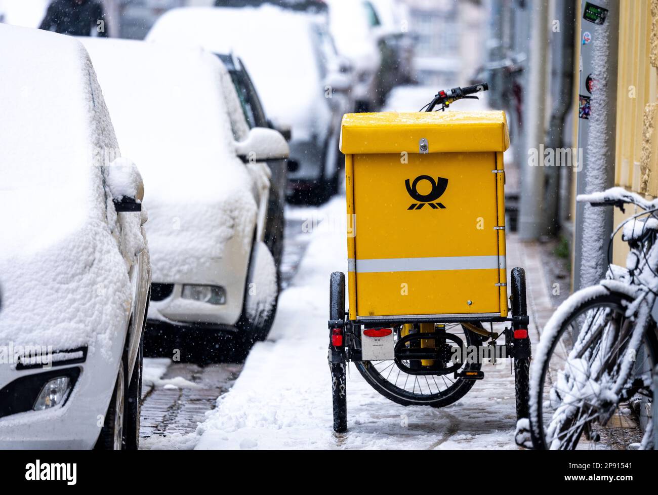 Schwerin, Allemagne. 10th mars 2023. Un vélo de transport de lettres est stationné sur le trottoir de la vieille ville en forte chute de neige. Sur 10 mars 2023, commence le quatrième cycle de négociations dans le conflit de négociation collective à Deutsche Post. Il s'agit d'une nouvelle convention collective pour environ 160 000 salariés de la division Post & Parcel Allemagne. Verdi exige 15 pour cent de plus d'argent. Credit: Jens Büttner/dpa/Alay Live News Banque D'Images