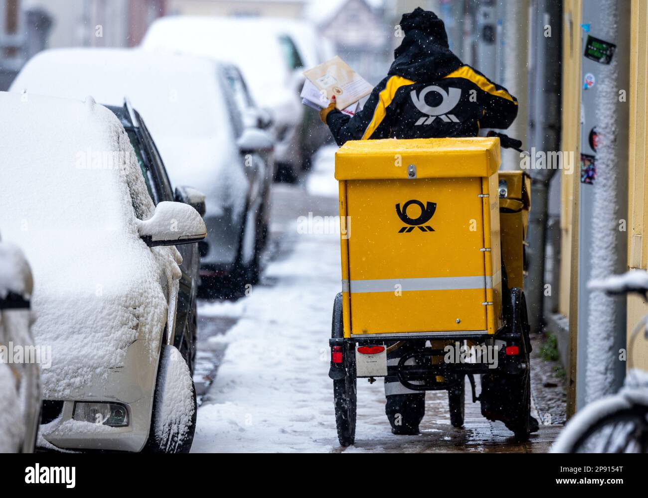 Schwerin, Allemagne. 10th mars 2023. Un porte-lettre est à son vélo dans la neige abondante dans la vieille ville. En ce qui concerne 10 mars 2023, commence le cycle de négociations de 4th dans le conflit de négociation collective à Deutsche Post. Il s'agit d'une nouvelle convention collective pour environ 160 000 salariés de la division Post & Paket Deutschland Group. Verdi exige une augmentation de salaire de 15 pour cent. Credit: Jens Büttner/dpa/Alay Live News Banque D'Images