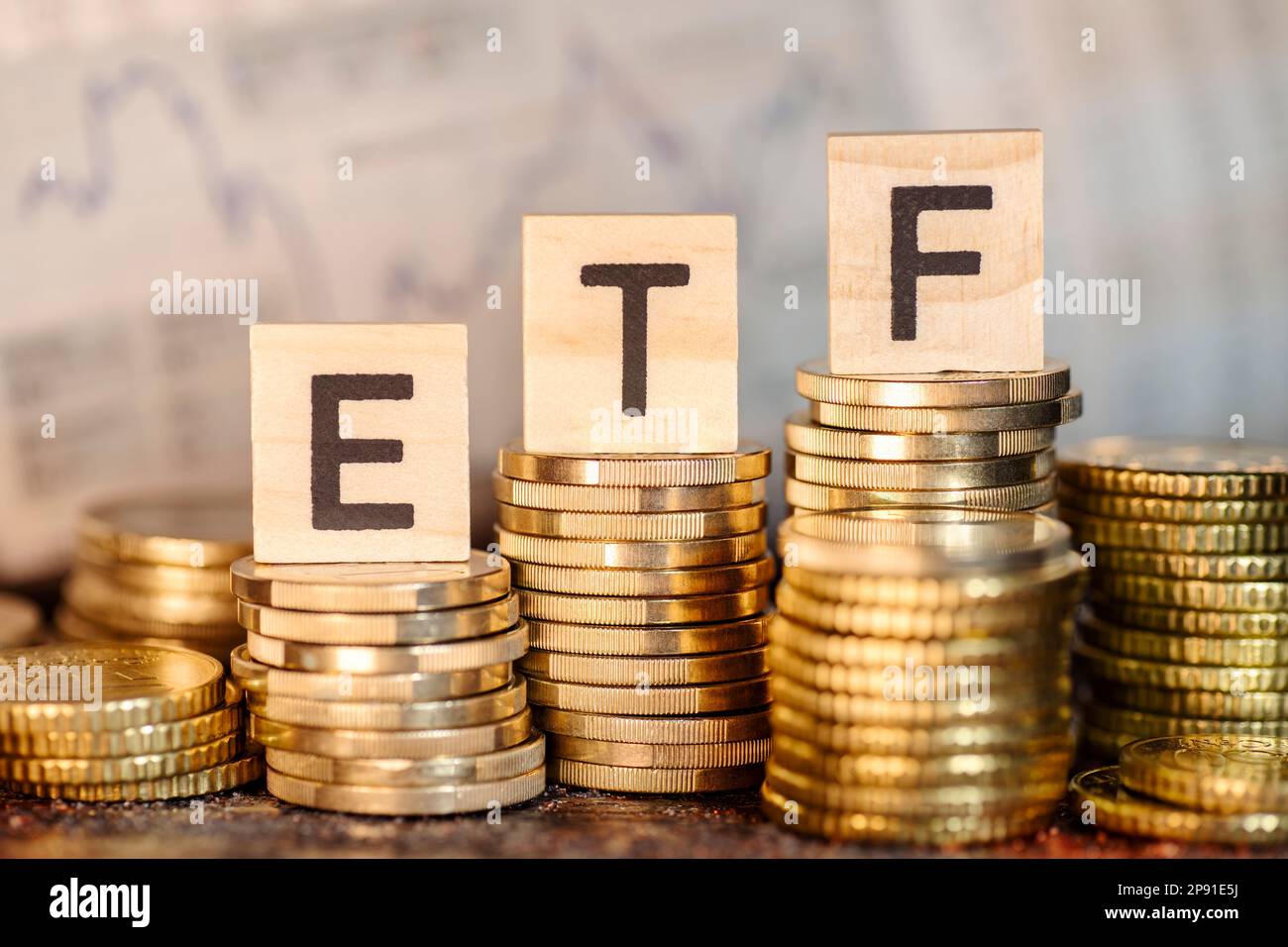 Plusieurs piles avec des pièces et le terme ETF et un graphique avec les cours des actions. Banque D'Images