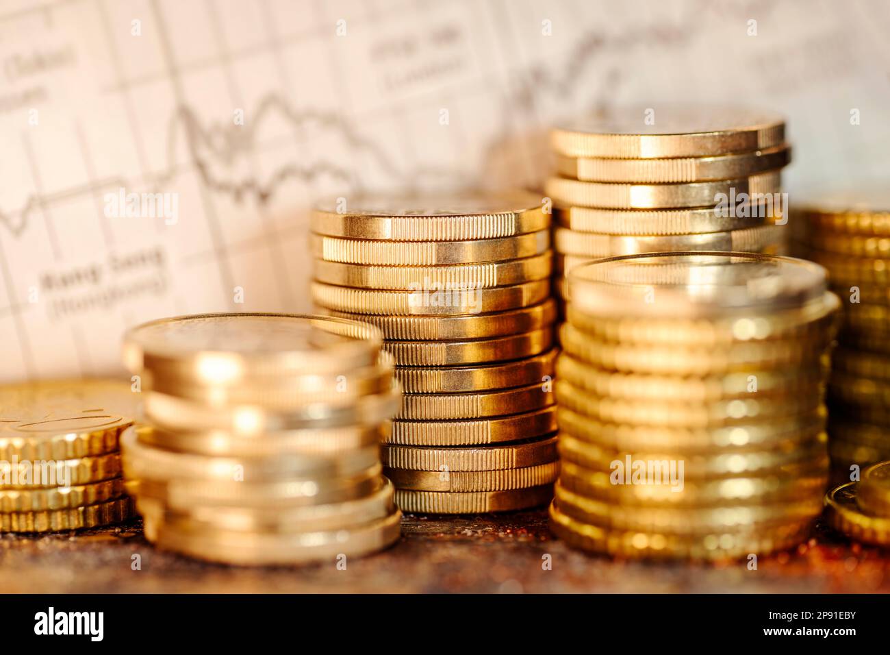 Plusieurs piles de pièces et graphique avec les prix boursiers. Des profits élevés sur les bourses internationales Banque D'Images