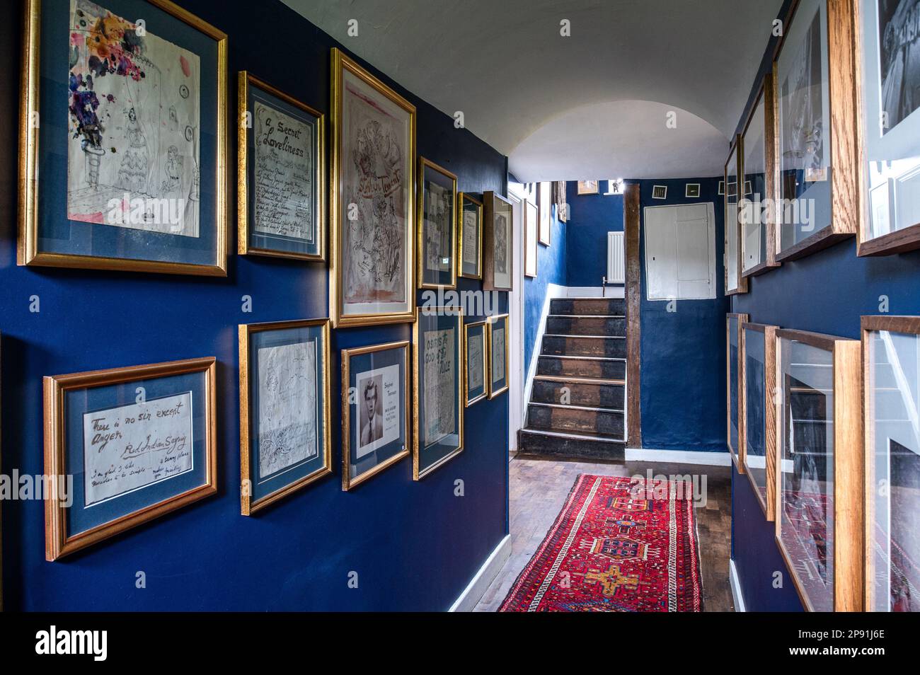 Murs bleu Oxford dans le couloir avec des photos de Cecil Beaton et des dessins de Stephen Tennant dans la ferme Tudor du 16th siècle, Suffolk, Royaume-Uni Banque D'Images