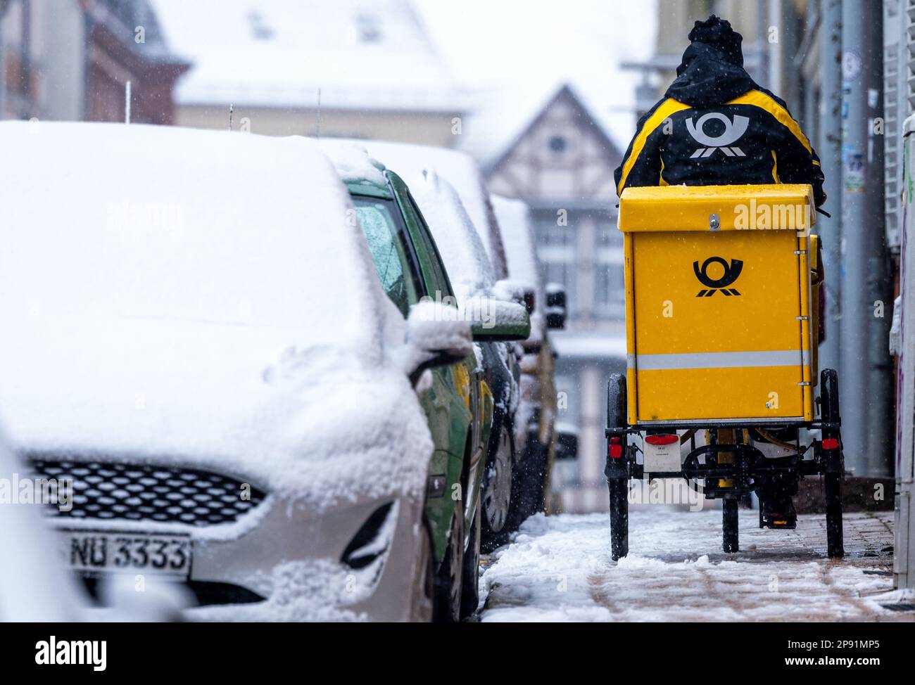 Schwerin, Allemagne. 10th mars 2023. Un porte-lettre est à son vélo dans la neige abondante dans la vieille ville. En ce qui concerne 10 mars 2023, commence le cycle de négociations de 4th dans le conflit de négociation collective à Deutsche Post. Il s'agit d'une nouvelle convention collective pour environ 160 000 salariés de la division Post & Paket Deutschland Group. Verdi exige une augmentation de salaire de 15 pour cent. Credit: Jens Büttner/dpa/Alay Live News Banque D'Images
