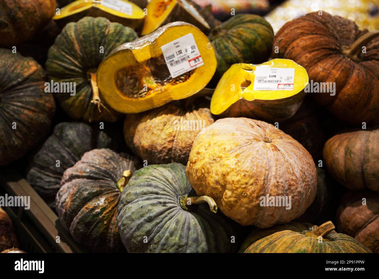 Tas de citrouilles avec des étiquettes de prix dans un supermarché. Beaucoup de vert et brun des légumes entiers et en moitiés background Banque D'Images