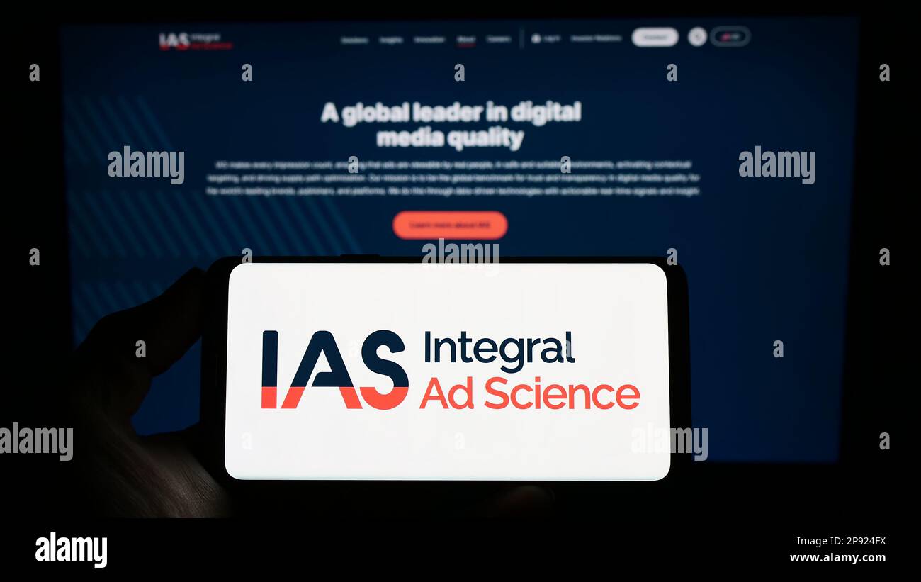 Personne détenant un smartphone avec le logo de la société américaine Integral ad Science Inc. (IAS) à l'écran en face du site Web. Mise au point sur l'affichage du téléphone. Banque D'Images