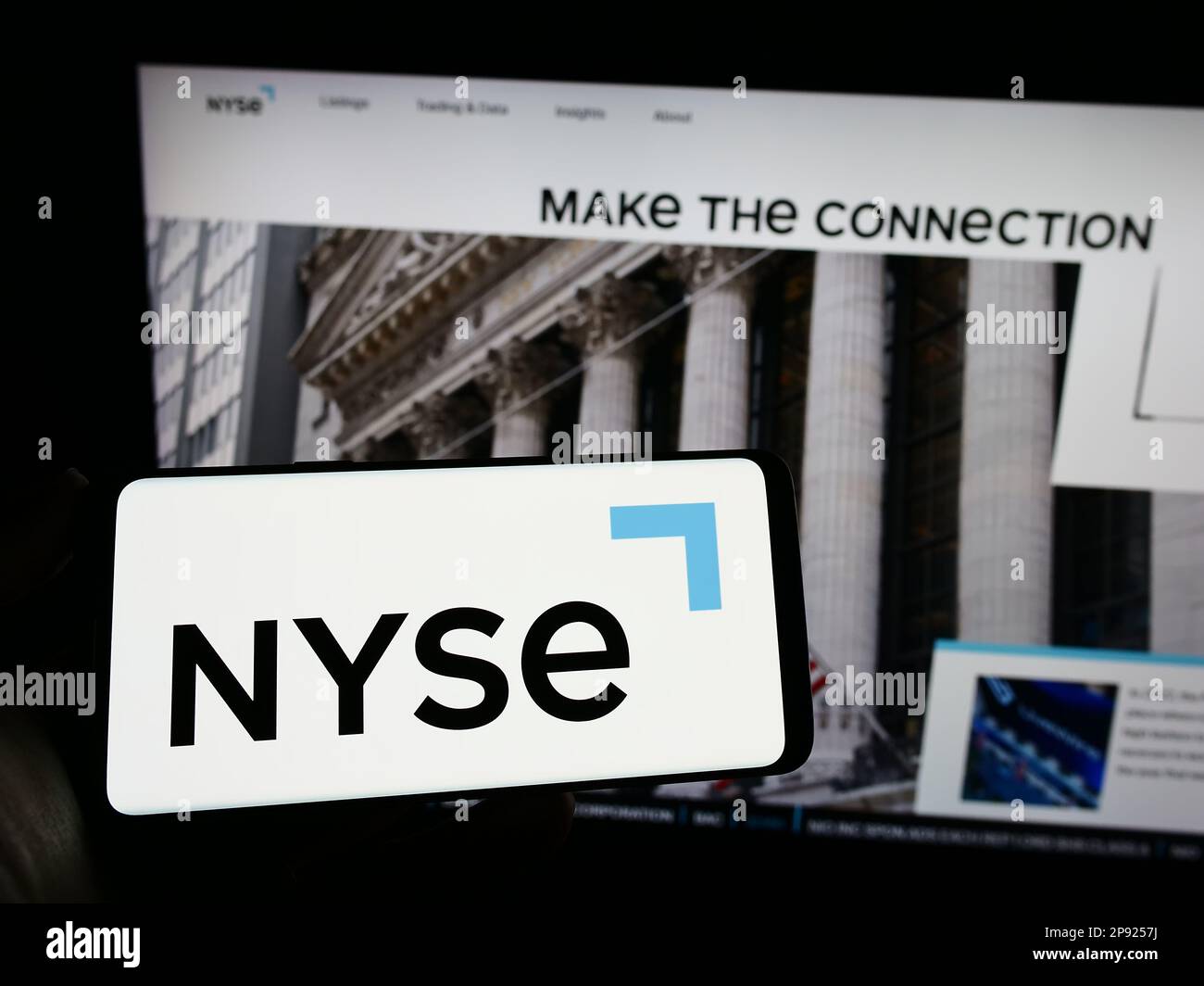 Personne tenant un smartphone avec le logo du marché américain New York stock Exchange (NYSE) sur l'écran devant le site Web. Mise au point sur l'affichage du téléphone. Banque D'Images