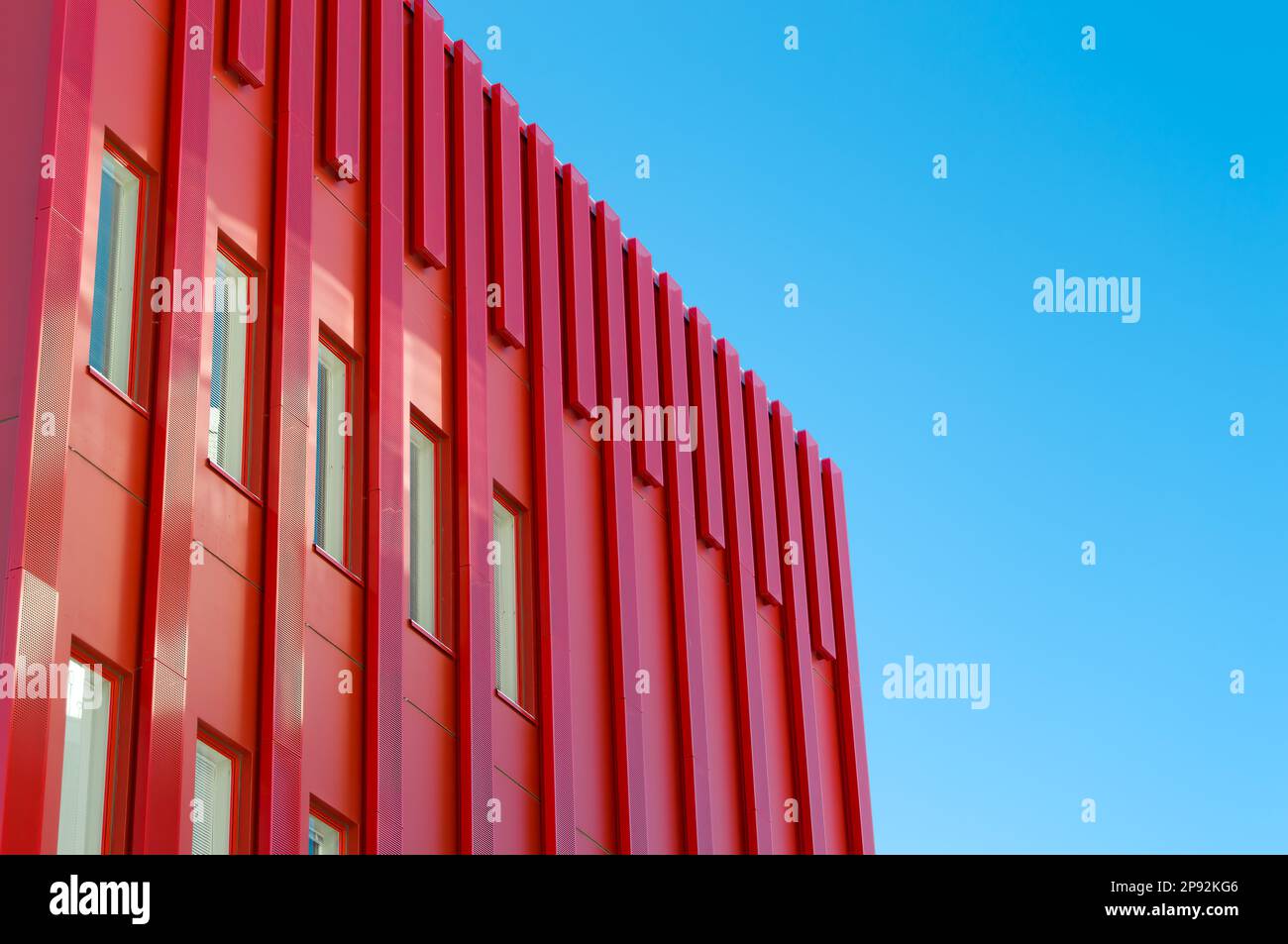 Bâtiment moderne de bureau architectural rouge. Tôles recouvrant l'extérieur de la structure. Bâtiment unique de style futuriste. Ciel dégagé à l'arrière Banque D'Images