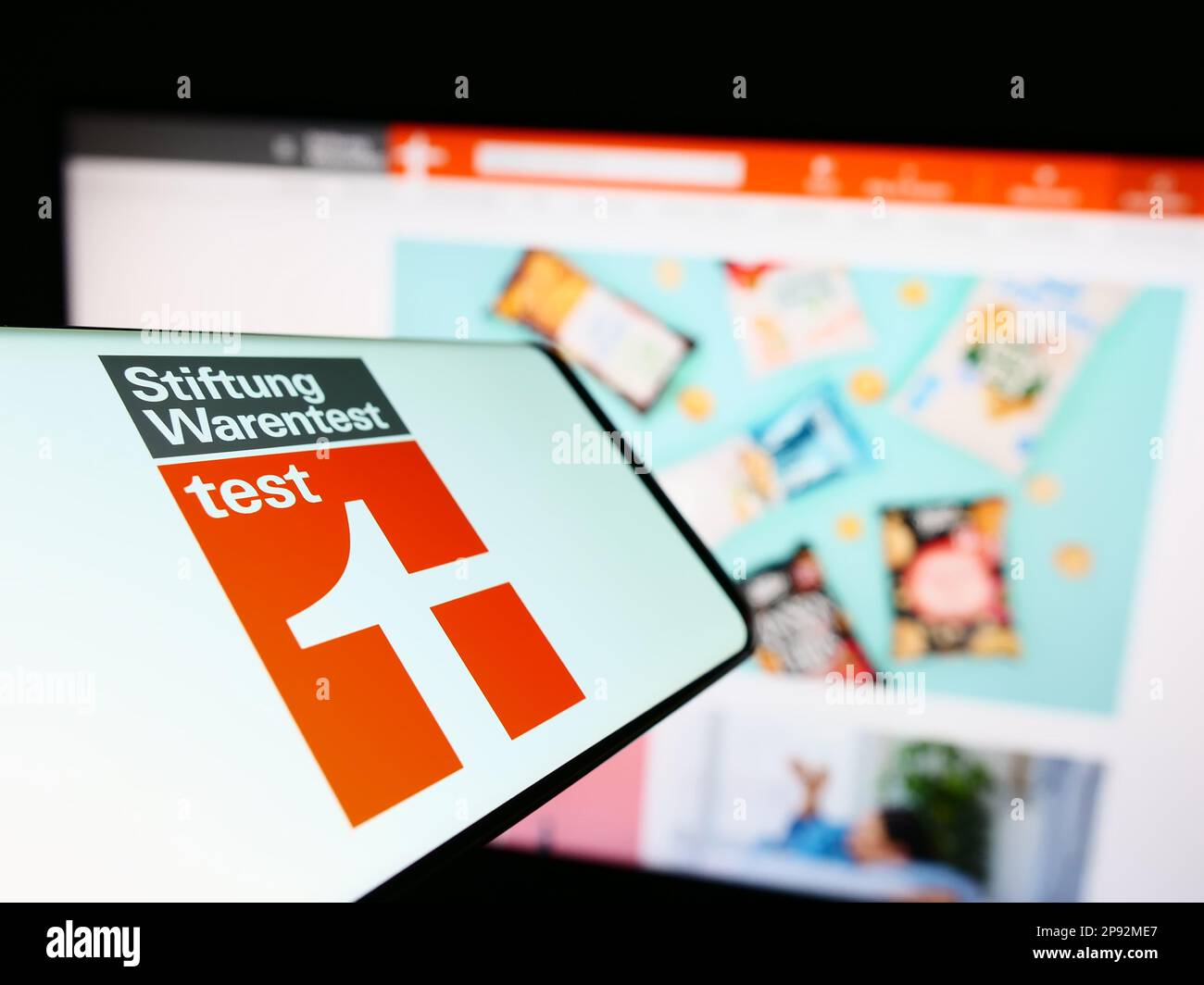 Téléphone portable avec logo de l'organisation allemande des consommateurs Stiftung Warentest à l'écran devant le site. Mise au point au centre-gauche de l'écran du téléphone. Banque D'Images