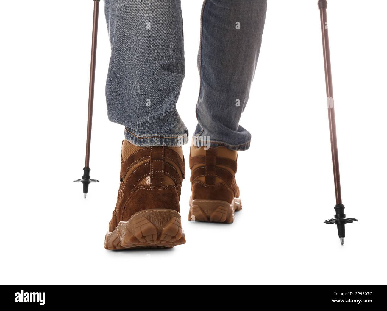 Homme portant des chaussures de randonnée élégantes avec des bâtons de randonnée sur fond blanc, gros plan Banque D'Images