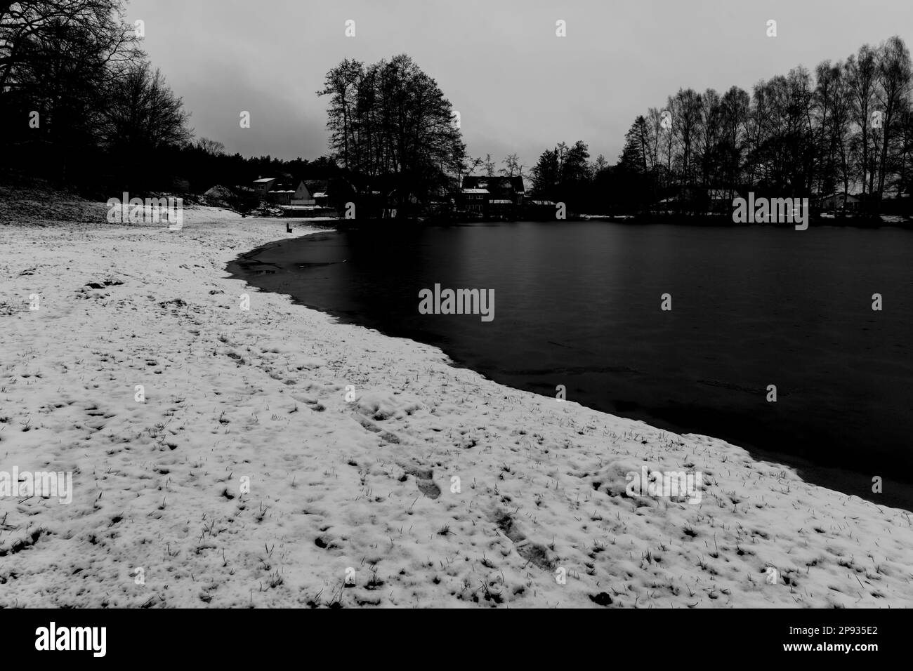 Petit lac de village en hiver, lac gelé, plage enneigée, noir/blanc Banque D'Images