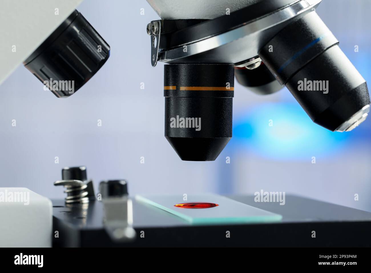 Lame de verre avec échantillon de liquide rouge sous microscope en laboratoire, gros plan Banque D'Images