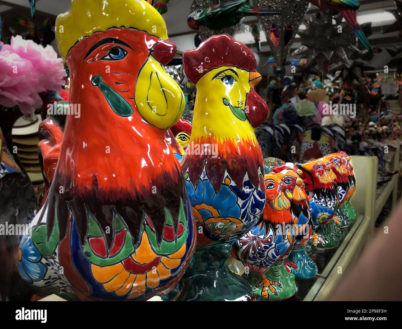 De nombreux poulets en céramique peints et colorés accrochés à un mur et à vendre dans un magasin de bazar mexicain. Banque D'Images