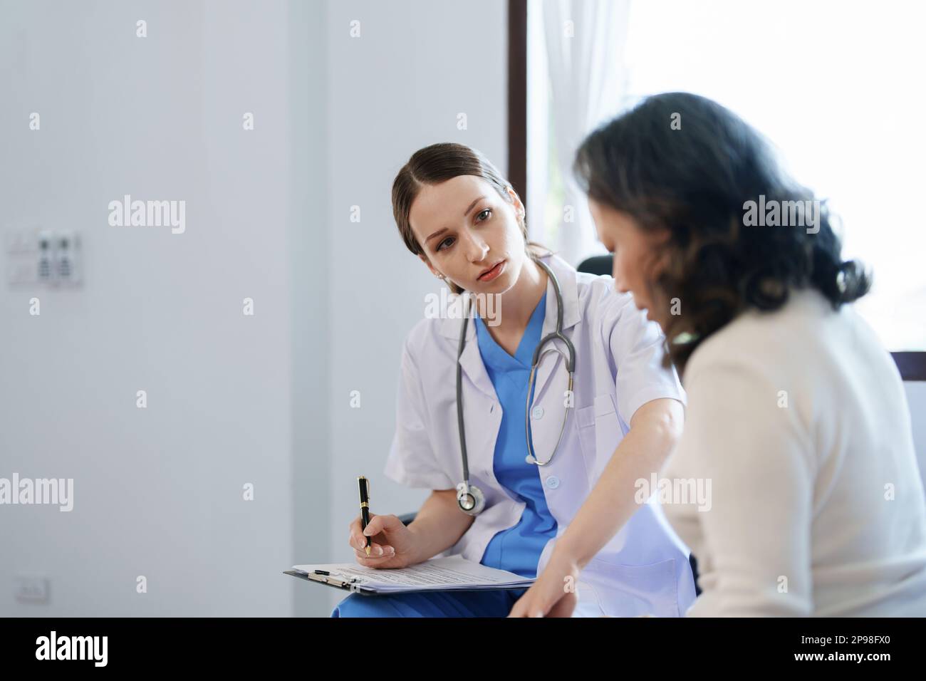 Portrait d'une femme médecin parlant à un patient souffrant de douleurs au genou. Banque D'Images