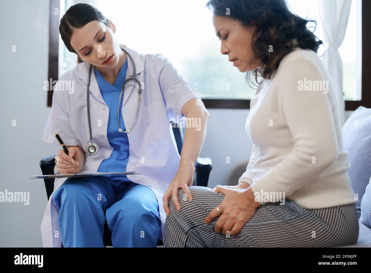 Portrait d'une femme médecin parlant à un patient souffrant de douleurs au genou. Banque D'Images