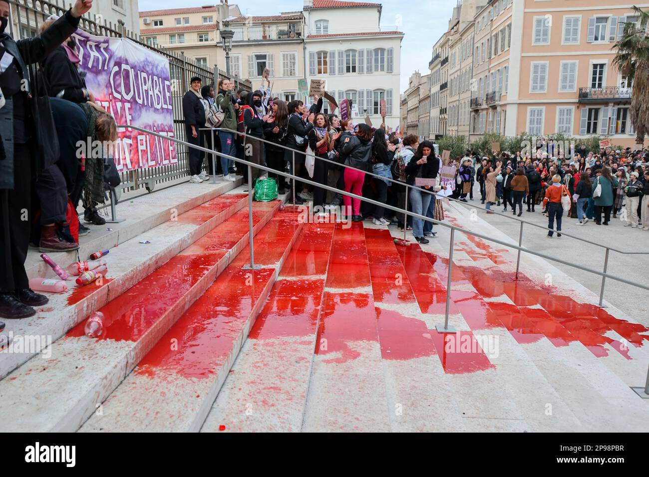 Les manifestants accrochent une bannière à la porte du palais de justice de Marseille et versent de la teinture rouge sur les marches représentant le sang des victimes du féminisme. À l'occasion de la Journée internationale des droits de la femme, plusieurs personnes ont manifesté dans les rues de Marseille. Banque D'Images